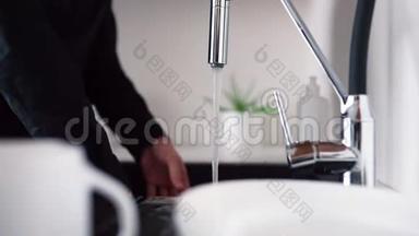 用海绵和手清洁白板的过程。 一个人站在水槽里，用水打开水龙头。 结束之后